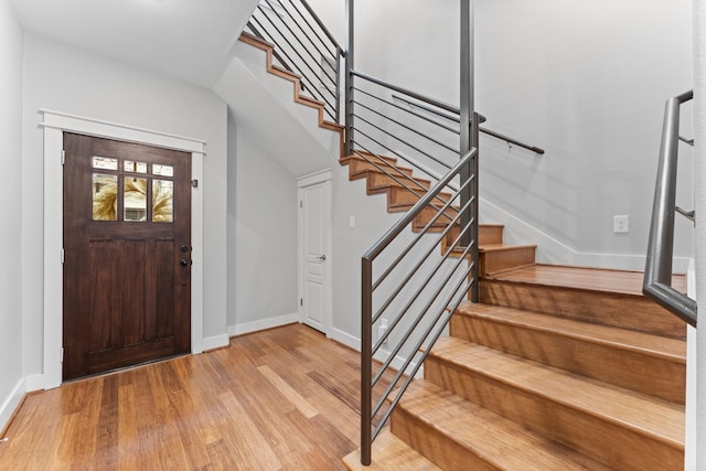 entrance foyer featuring stairs, baseboards, and light wood finished floors