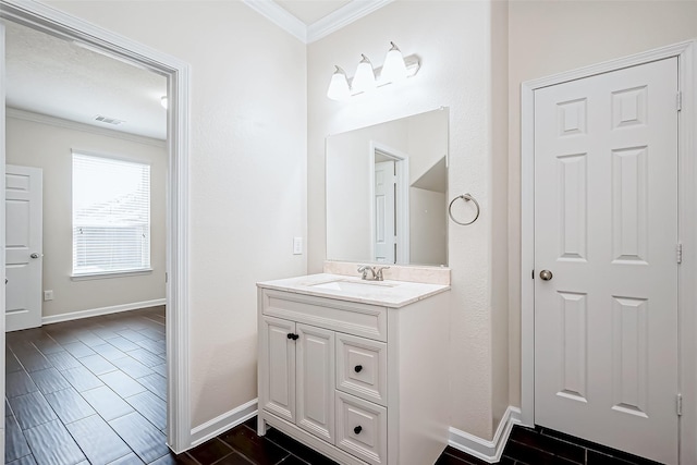 bathroom featuring vanity, ornamental molding, baseboards, and visible vents