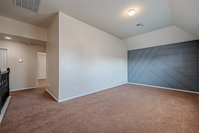carpeted empty room with visible vents, baseboards, and lofted ceiling