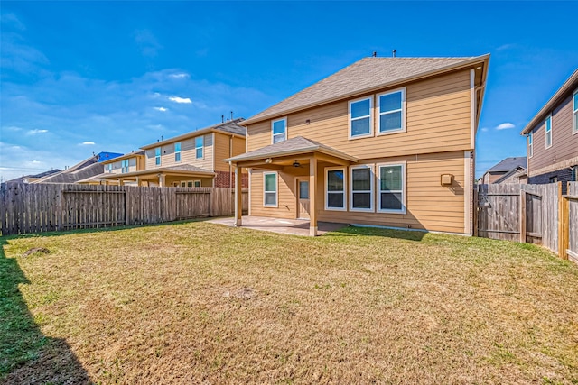 rear view of property with a fenced backyard, a shingled roof, a lawn, and a patio area