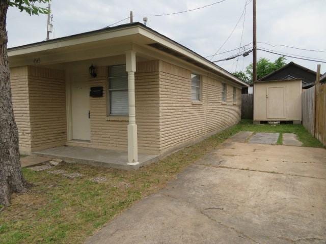 view of side of home with a storage shed, fence, and an outbuilding