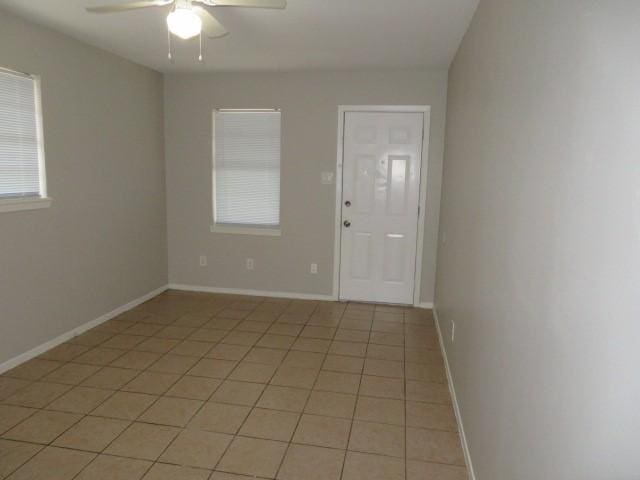 unfurnished room with a ceiling fan, baseboards, and light tile patterned floors