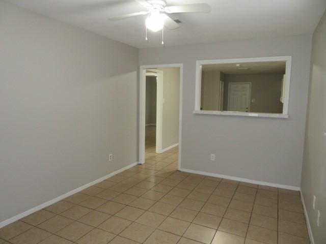 spare room with light tile patterned floors, baseboards, and ceiling fan