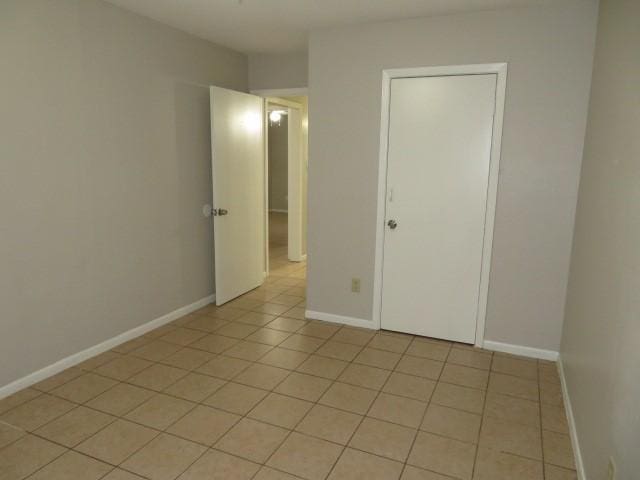spare room featuring baseboards and light tile patterned floors