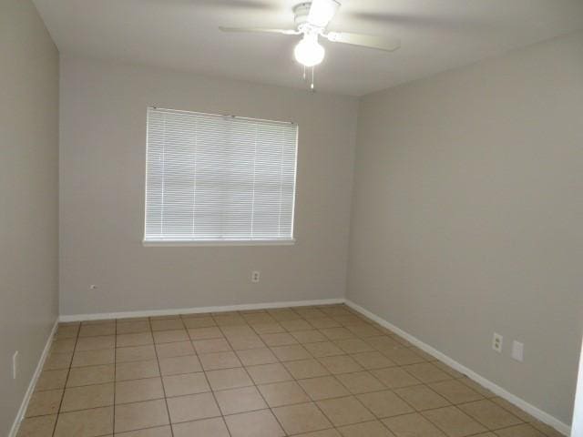 spare room featuring a ceiling fan, baseboards, and light tile patterned flooring