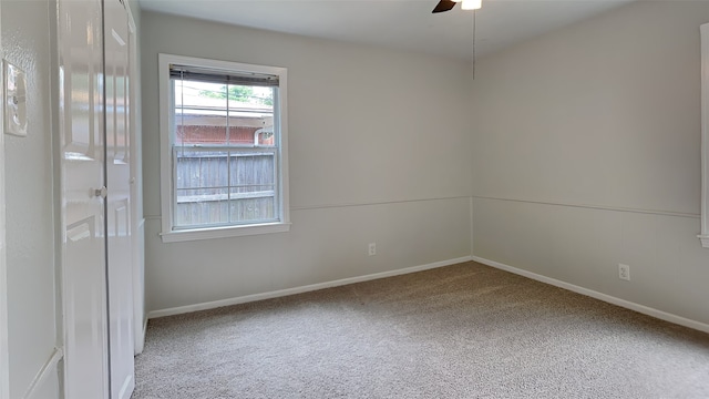 carpeted empty room featuring baseboards and a ceiling fan