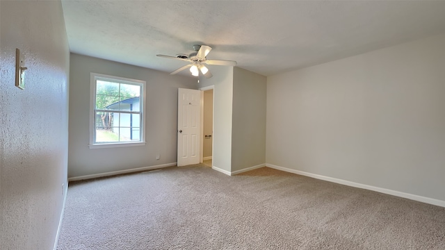 carpeted empty room with ceiling fan and baseboards