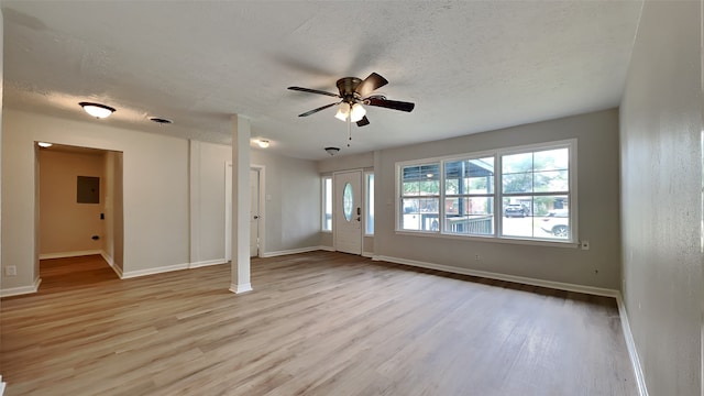 unfurnished living room featuring light wood-style flooring, a textured ceiling, ceiling fan, baseboards, and electric panel
