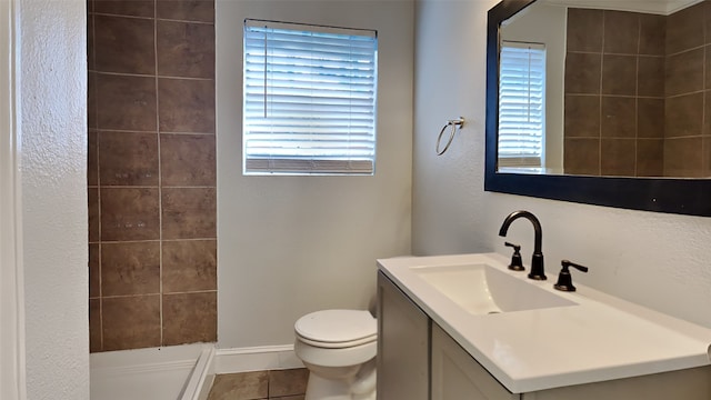 bathroom featuring vanity, tile patterned flooring, toilet, tiled shower, and a textured wall
