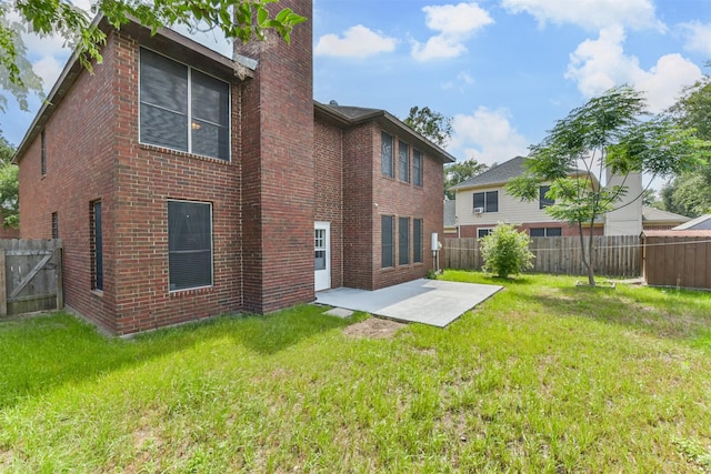 rear view of property featuring a lawn, a fenced backyard, a patio area, and brick siding