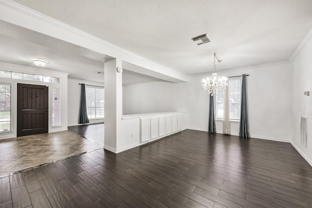 interior space with crown molding, dark wood-style flooring, a chandelier, baseboards, and visible vents