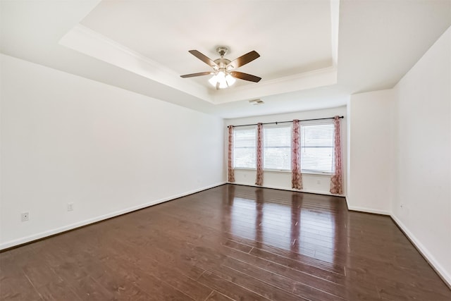 unfurnished room featuring a ceiling fan, visible vents, wood finished floors, a raised ceiling, and baseboards