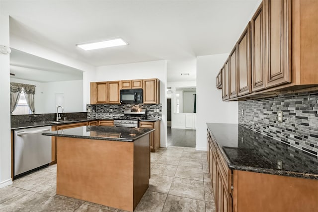 kitchen featuring a sink, appliances with stainless steel finishes, decorative backsplash, and dark stone counters