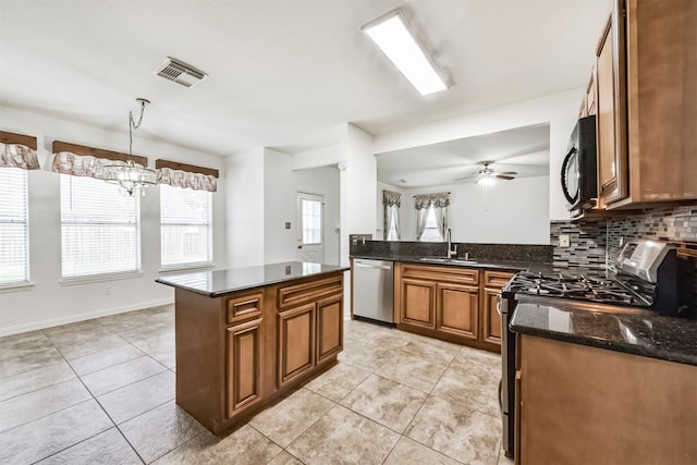 kitchen with brown cabinetry, light tile patterned floors, a sink, appliances with stainless steel finishes, and backsplash