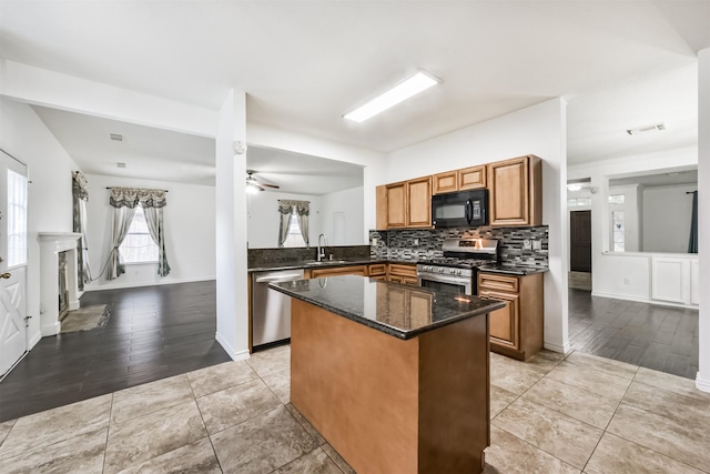 kitchen with a kitchen island, appliances with stainless steel finishes, tasteful backsplash, brown cabinets, and a sink