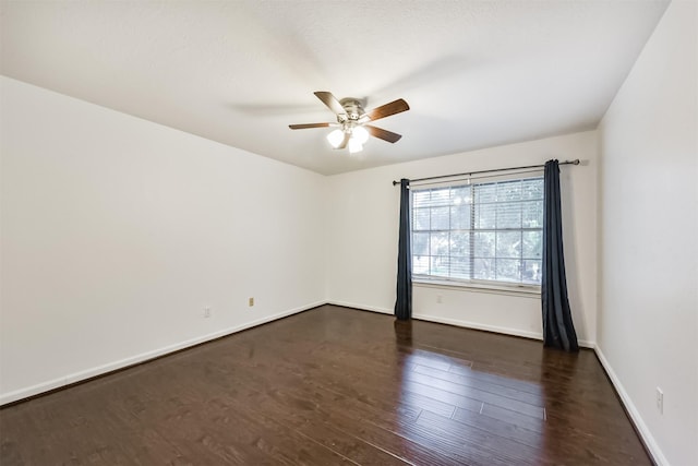 spare room with baseboards, a ceiling fan, and dark wood-style flooring