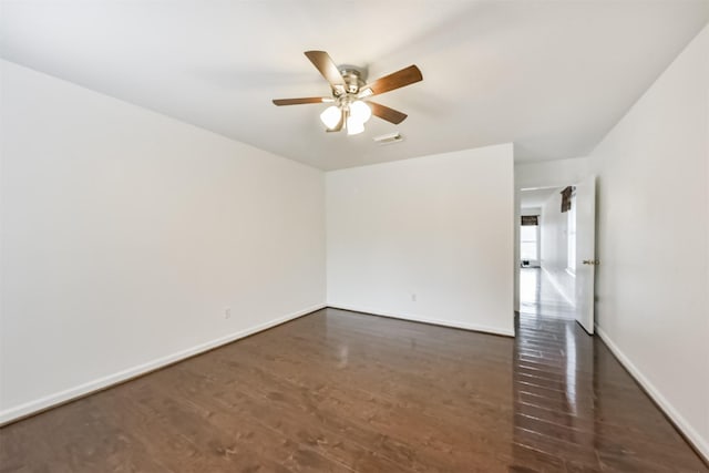 empty room with visible vents, dark wood-style flooring, ceiling fan, and baseboards