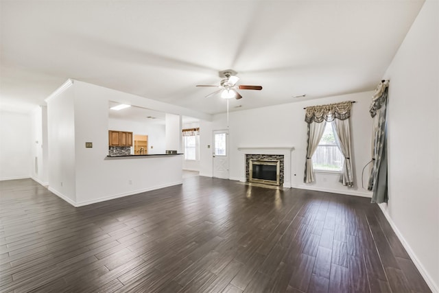unfurnished living room with a healthy amount of sunlight, a ceiling fan, and dark wood-type flooring