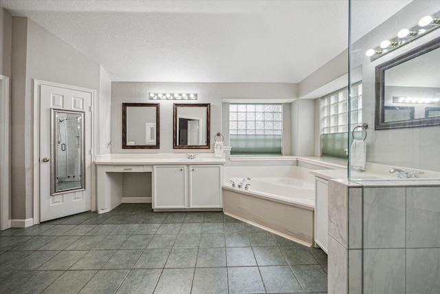 bathroom featuring vanity, a textured ceiling, a garden tub, and tile patterned flooring