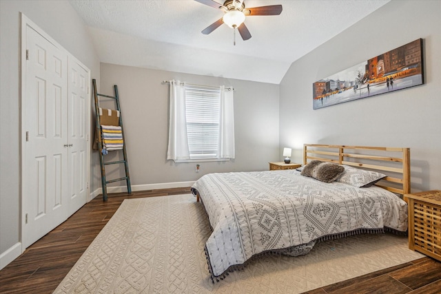 bedroom featuring vaulted ceiling, a closet, baseboards, ceiling fan, and wood finished floors