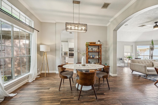 dining room featuring plenty of natural light, arched walkways, baseboards, and visible vents