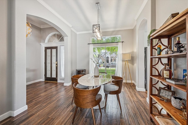 dining room with dark wood-style floors, crown molding, arched walkways, and baseboards