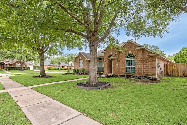 view of front of home featuring fence, a front lawn, and brick siding