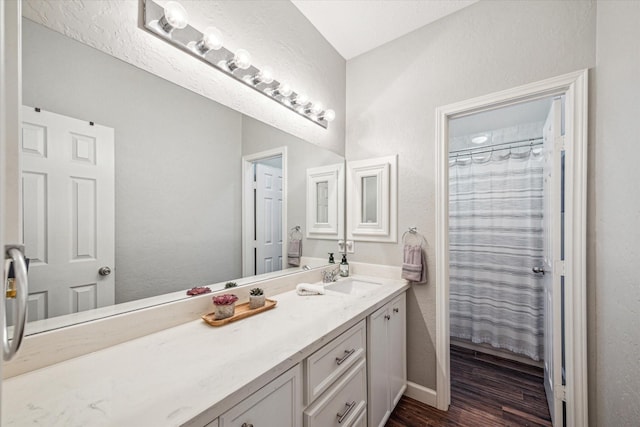 bathroom featuring curtained shower, baseboards, wood finished floors, and vanity