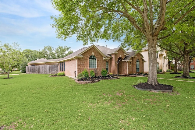 ranch-style home with fence, brick siding, and a front yard