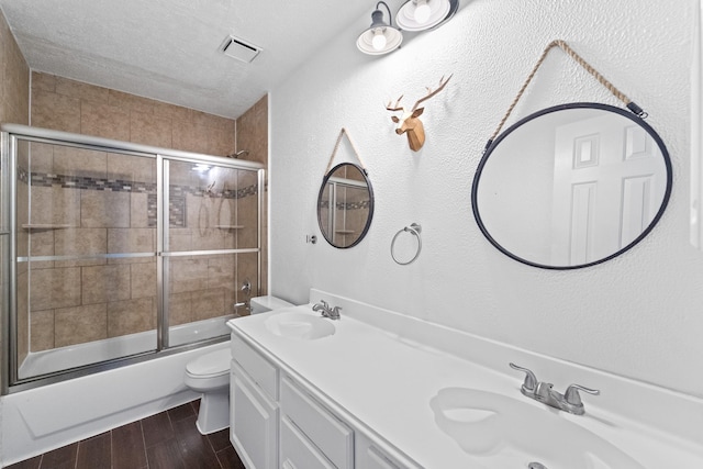full bath with a sink, toilet, shower / bath combination with glass door, and wood finished floors
