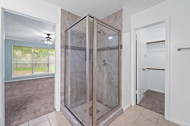 full bathroom with a walk in closet, a ceiling fan, a textured ceiling, tile patterned flooring, and a stall shower