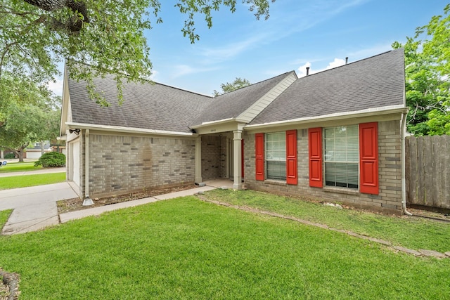 view of front of house featuring a garage, a front lawn, fence, roof with shingles, and brick siding