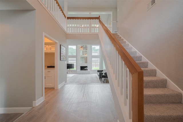 1709 Coles Farm Dr, Sugar Land, TX 77478 - staircase with ceiling fan, a brick fireplace, a high ceiling, baseboards, and wood finished floors