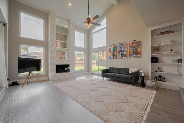 1709 Coles Farm Dr, Sugar Land, TX 77478 - living area featuring wood finished floors, a ceiling fan, high vaulted ceiling, built in features, and a brick fireplace