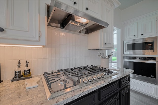 1709 Coles Farm Dr, Sugar Land, TX 77478 - kitchen featuring stainless steel appliances, under cabinet range hood, dark cabinets, white cabinetry, and decorative backsplash