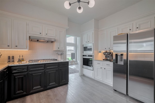 1709 Coles Farm Dr, Sugar Land, TX 77478 - kitchen featuring appliances with stainless steel finishes, dark cabinetry, under cabinet range hood, white cabinetry, and a chandelier