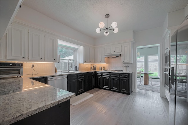 1709 Coles Farm Dr, Sugar Land, TX 77478 - kitchen with stainless steel appliances, dark cabinets, white cabinets, a chandelier, and a textured ceiling