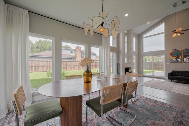 1709 Coles Farm Dr, Sugar Land, TX 77478 - dining room featuring a chandelier, a brick fireplace, wood finished floors, recessed lighting, and high vaulted ceiling
