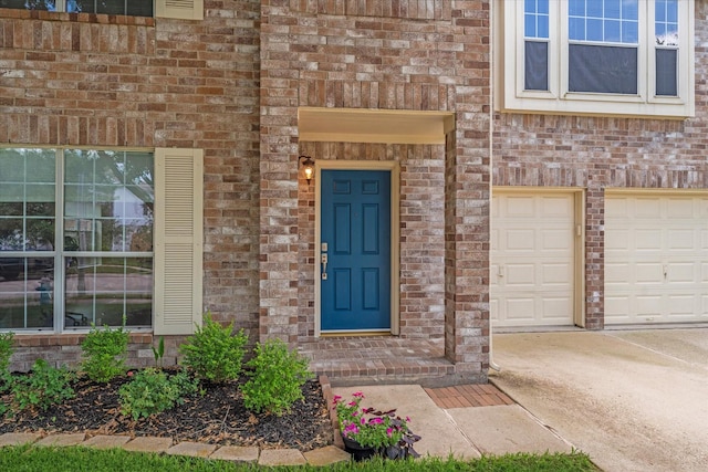 doorway to property with brick siding, concrete driveway, and an attached garage