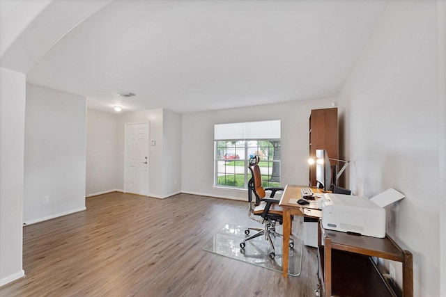 office featuring wood finished floors, baseboards, and arched walkways