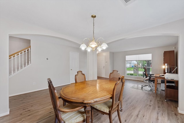 dining area with arched walkways, a chandelier, light wood-type flooring, stairway, and an office area