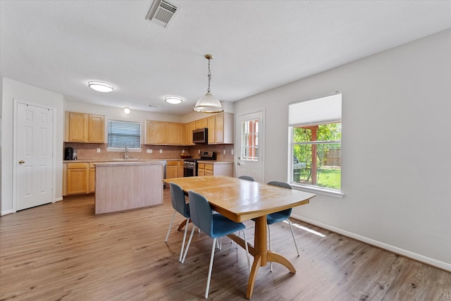 dining space with light wood-type flooring and baseboards