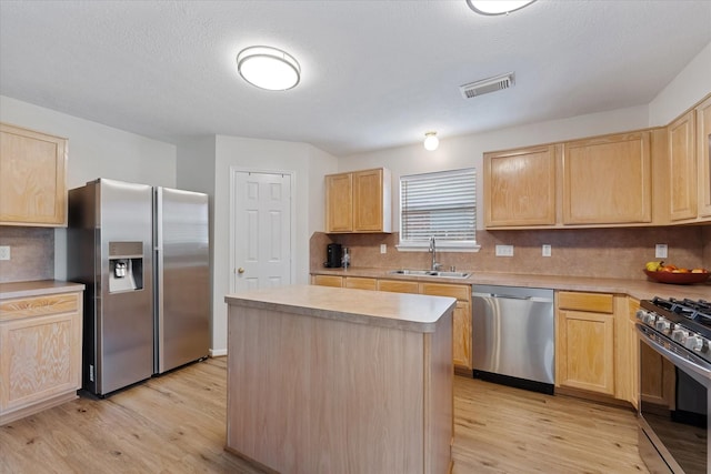 kitchen with stainless steel appliances, a sink, light brown cabinetry, and light wood-type flooring