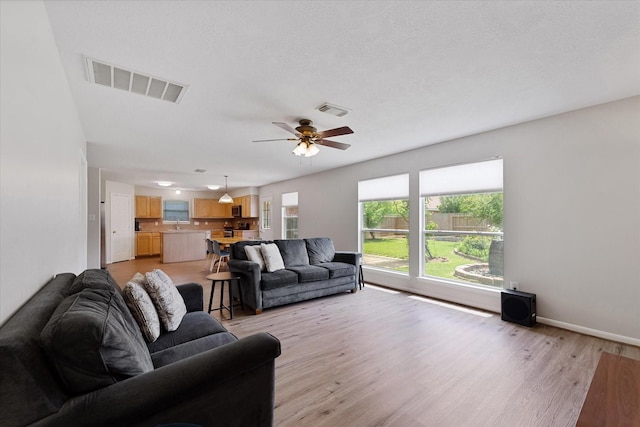 living area with light wood-style floors, ceiling fan, and baseboards