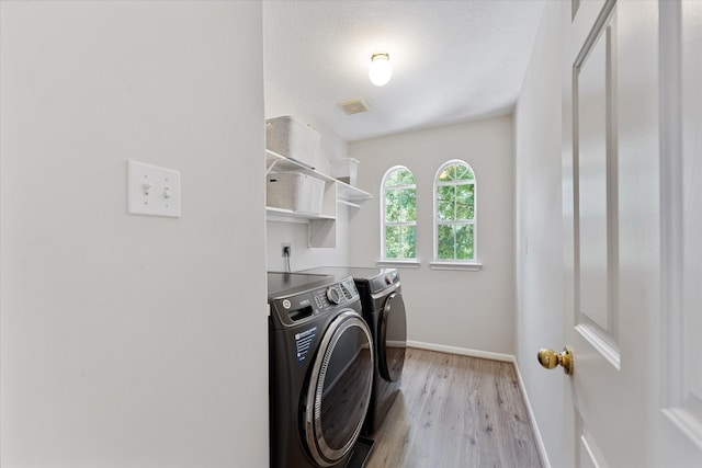 laundry room featuring washer and clothes dryer, baseboards, and light wood-style floors