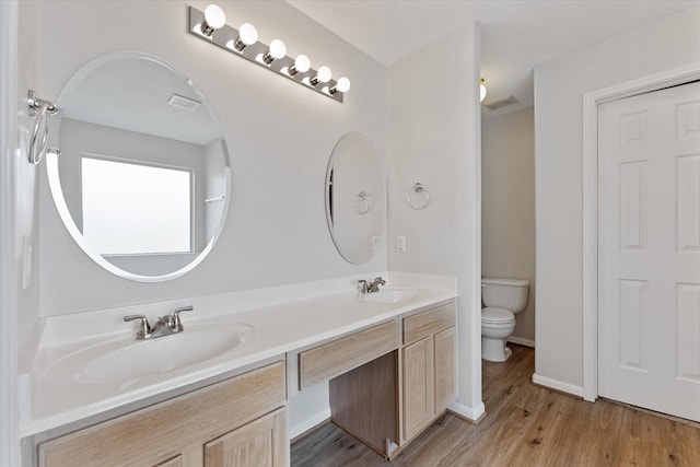 full bath featuring toilet, wood finished floors, double vanity, and baseboards