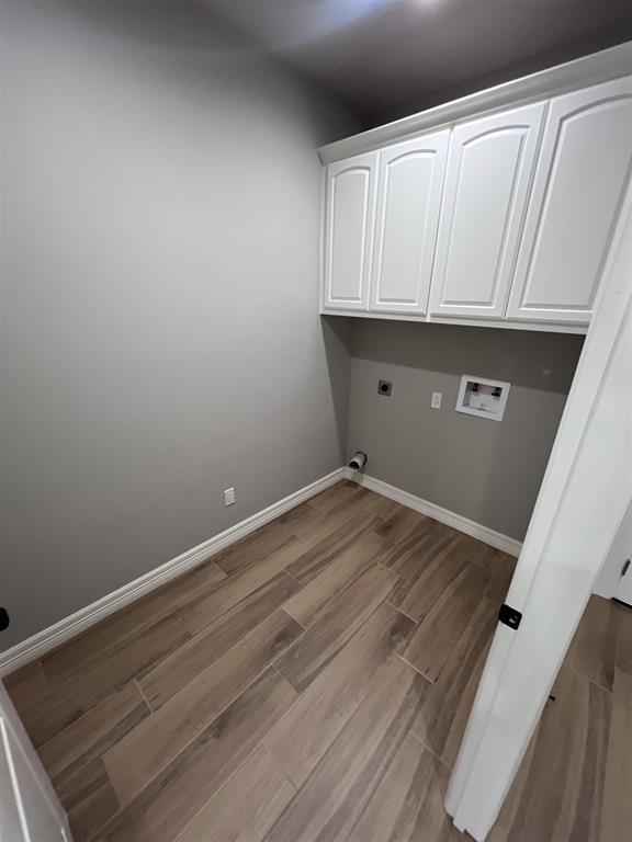 7510 Tram Rd, Beaumont, TX 77713 - washroom featuring cabinet space, hookup for a washing machine, baseboards, wood finished floors, and hookup for an electric dryer