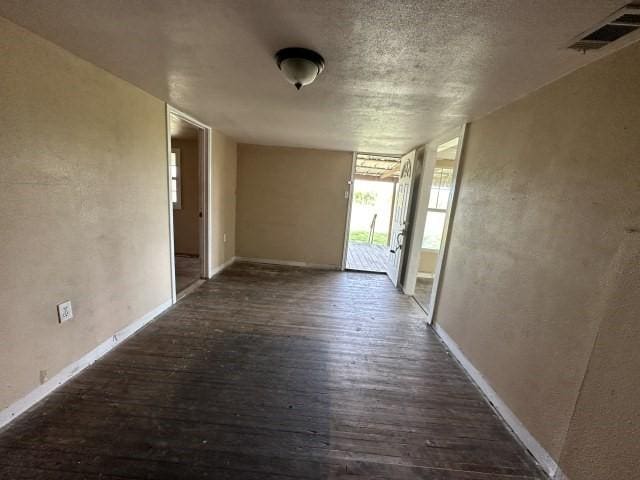 interior space with visible vents, a textured wall, wood finished floors, baseboards, and a textured ceiling