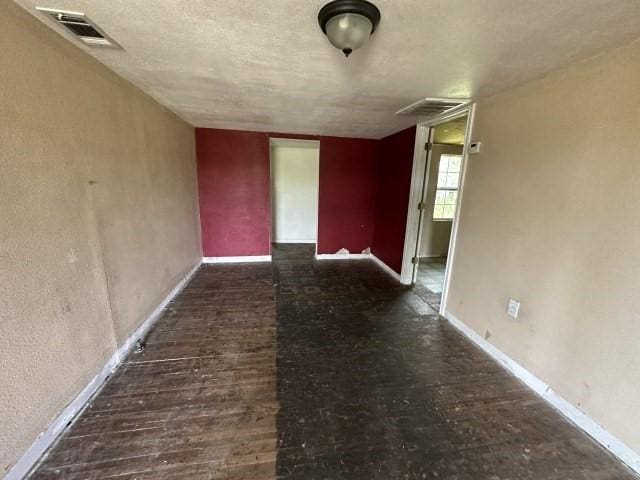 spare room featuring baseboards, visible vents, and wood finished floors