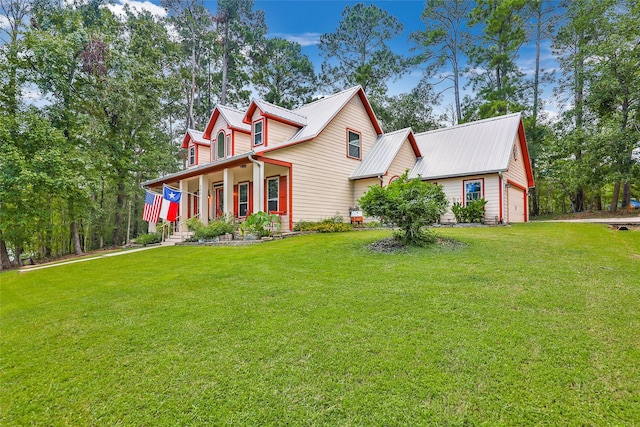 view of front of home with a porch, a garage, a front lawn, and metal roof